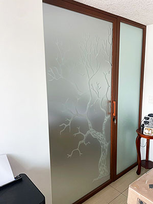Fabricación e instalación de una puerta en aluminio color madera y diseño de árbol
